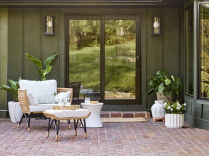 Pella Designer Series patio door with wood frame opening to outdoor patio, featuring large glass panels, natural light, and energy efficient design