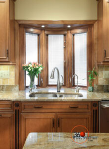 Pella Designer Series wood window installation in kitchen, showcasing bay style design, warm wood tones, and premium craftsmanship