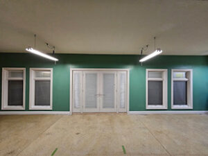 Pella Designer Series French patio door with matching wood windows installed in a residential interior, showcasing white frames and energy efficient glass